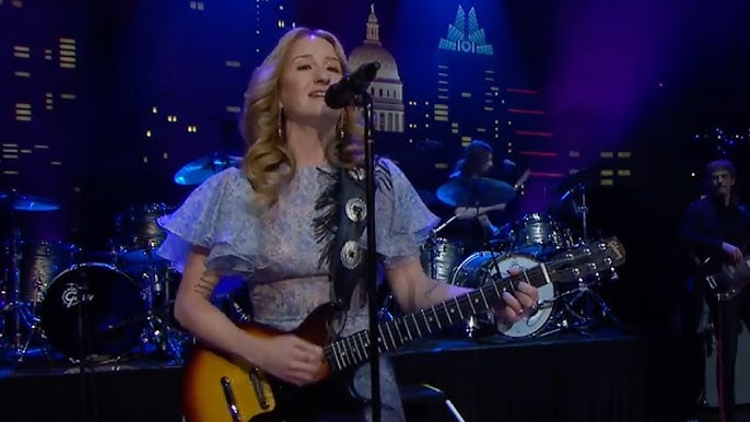 Margo Price performing on stage with guitar