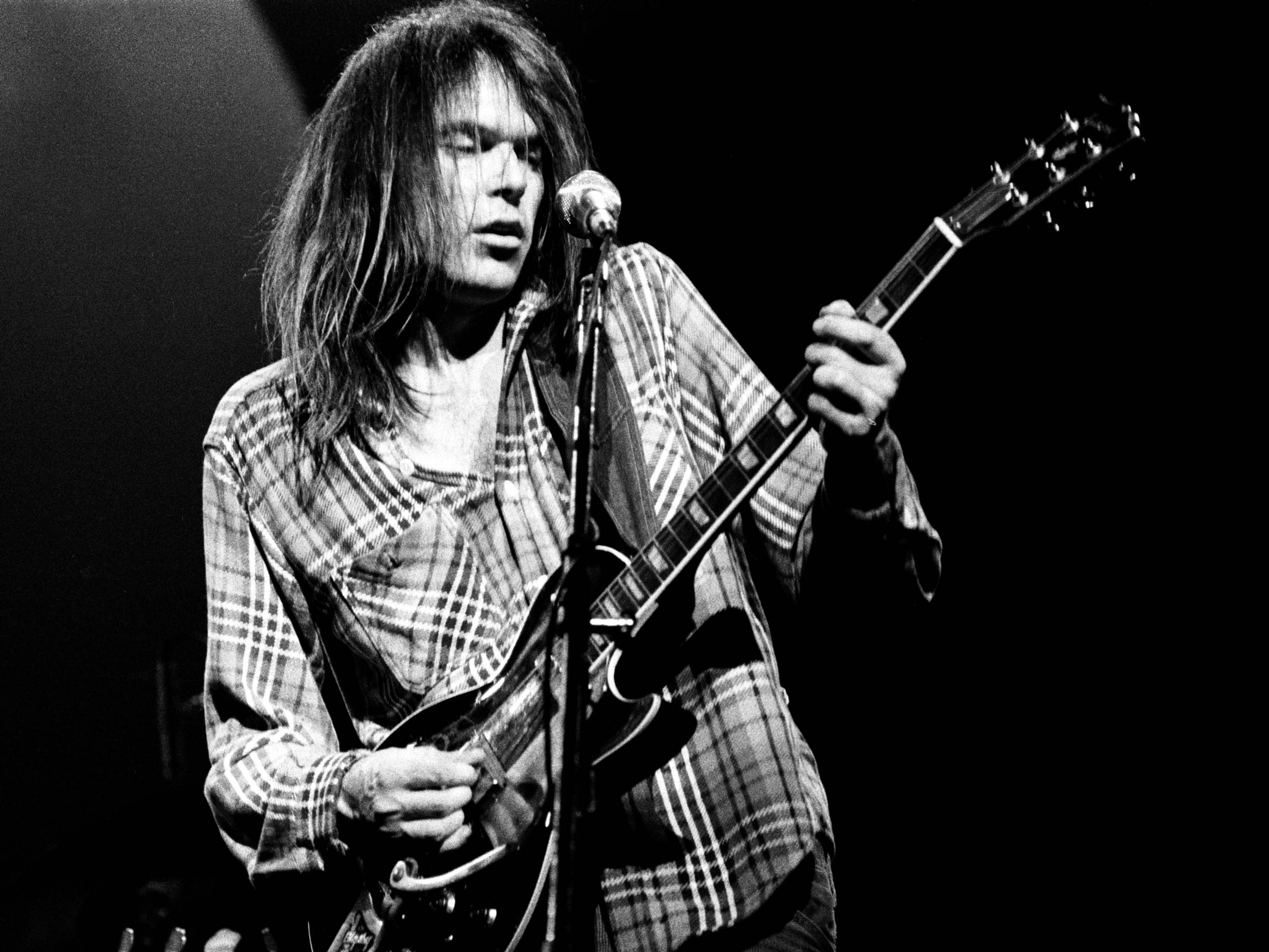 Neil Young performing live on stage with guitar