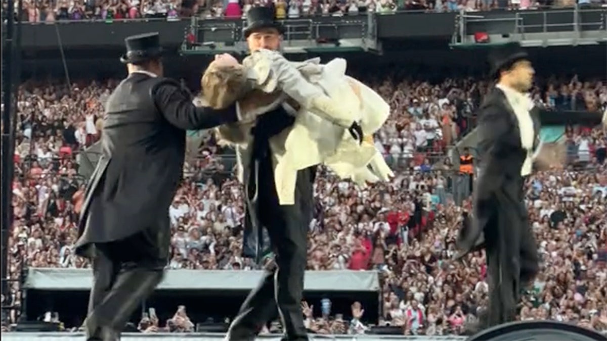 Taylor Swift performing on Eras Tour with Travis Kelce in audience